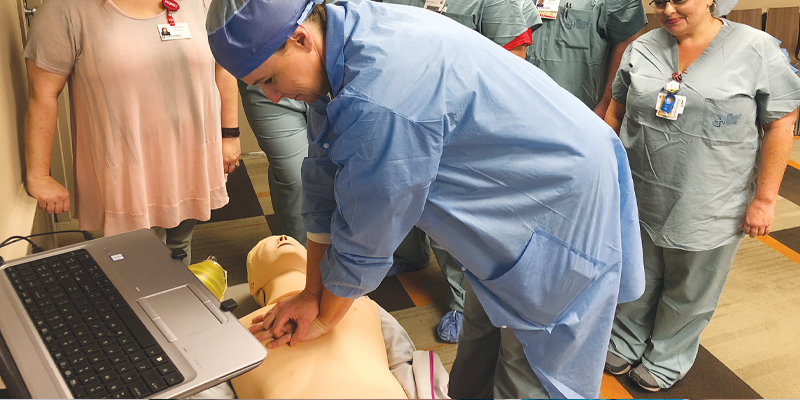 Medical training session with CPR manikin and healthcare professionals.
