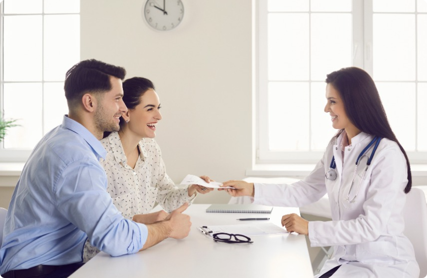 Doctor handing prescription to smiling couple in office.