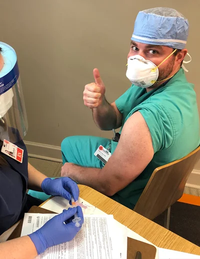 Healthcare worker giving thumbs up during vaccination.