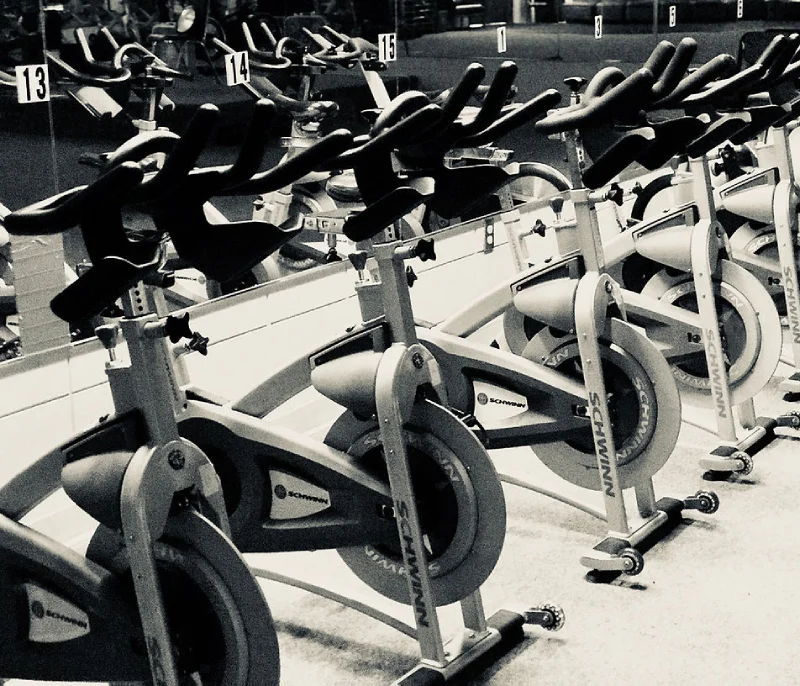 Row of indoor cycling exercise bikes in gym.