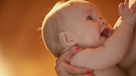 Infant holding finger, warm lighting.