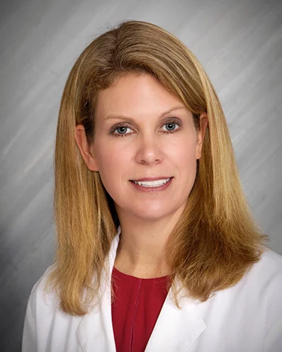 Professional woman in lab coat, portrait with neutral background.