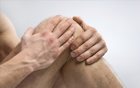 Person holding knee in pain or discomfort.