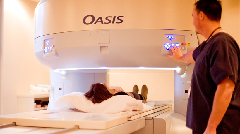 Technician operating MRI machine with patient lying down.