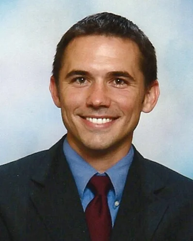 Smiling man in business suit with blue tie.