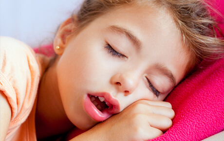 Child sleeping peacefully on pink pillow.