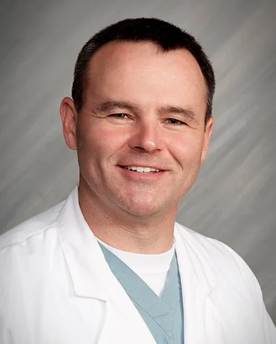 Smiling male doctor in white lab coat.