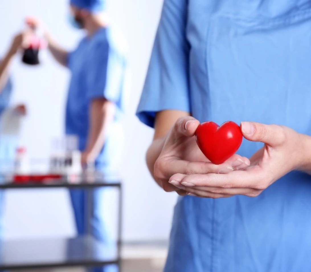 Medical professional holding a red heart in clinic.