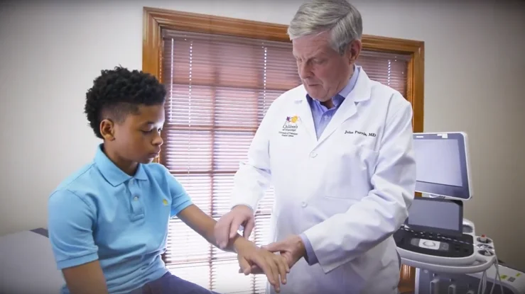 Doctor examining child's wrist in clinic.