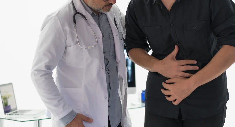 Doctor examining patient with stomach pain in clinic