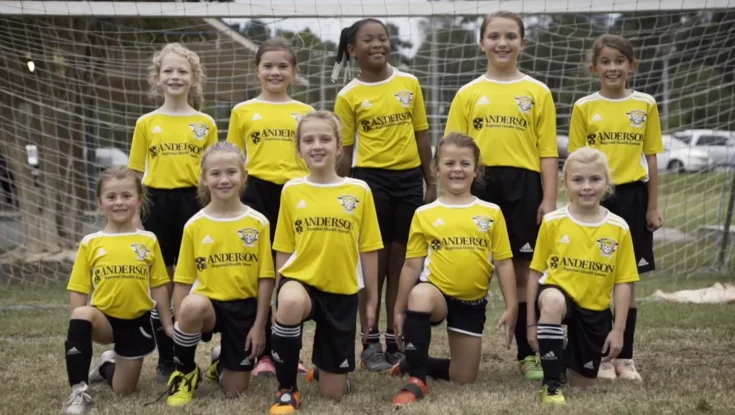 Youth soccer team posing in yellow uniforms.