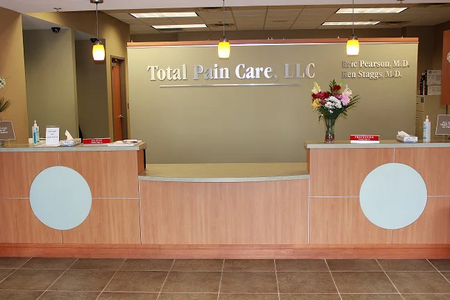 Pain clinic reception desk with signage and flowers.